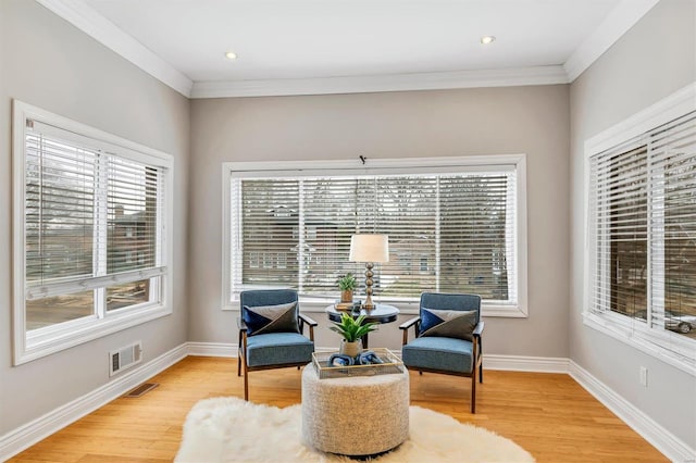 living area featuring a wealth of natural light, light wood finished floors, visible vents, and baseboards