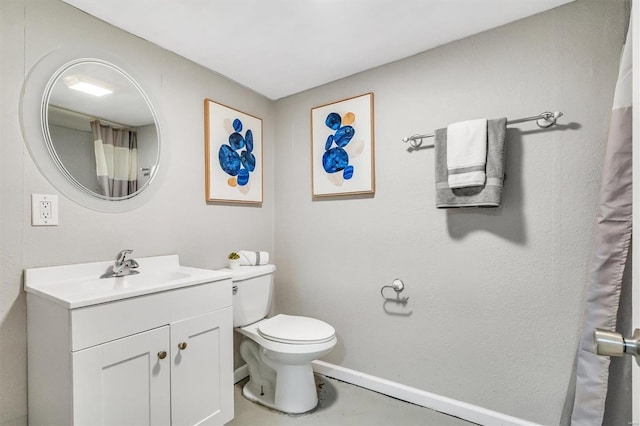 bathroom featuring toilet, baseboards, and vanity