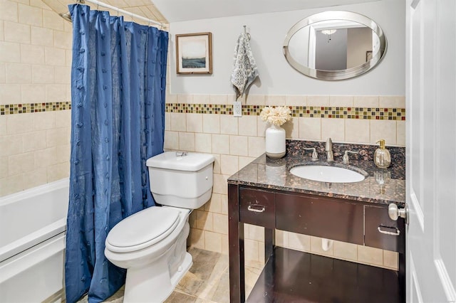 bathroom featuring toilet, shower / tub combo, vanity, tile walls, and wainscoting