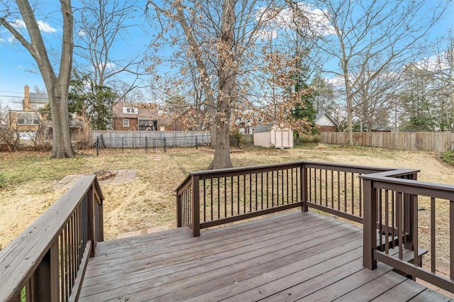 deck with a storage unit, a lawn, an outdoor structure, and a fenced backyard