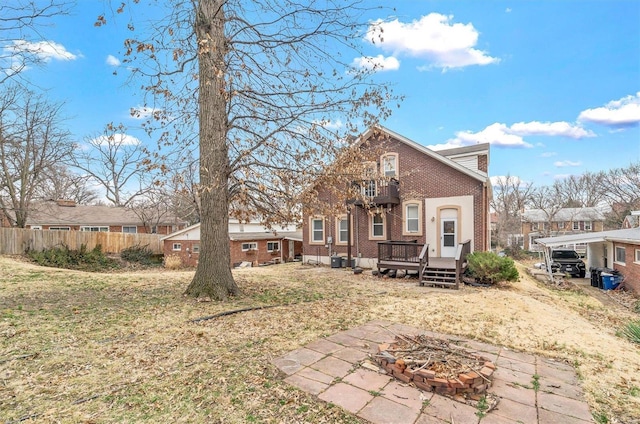 rear view of house featuring brick siding, fence, a deck, a balcony, and a fire pit