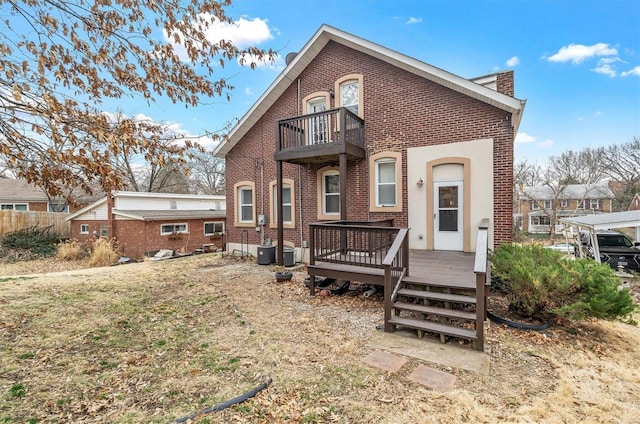 back of house with a chimney, brick siding, and a balcony