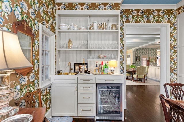 bar with wallpapered walls, a sink, beverage cooler, and indoor wet bar