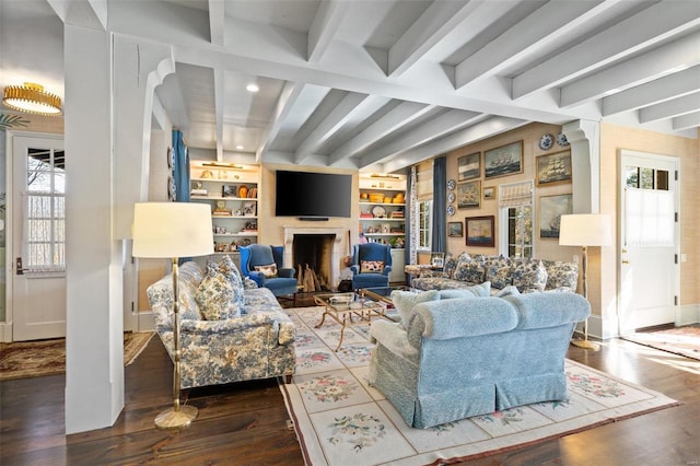 living area with beam ceiling, a fireplace, built in shelves, and wood finished floors