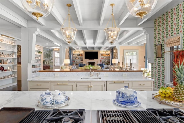 kitchen featuring light stone counters, plenty of natural light, a sink, a notable chandelier, and open floor plan