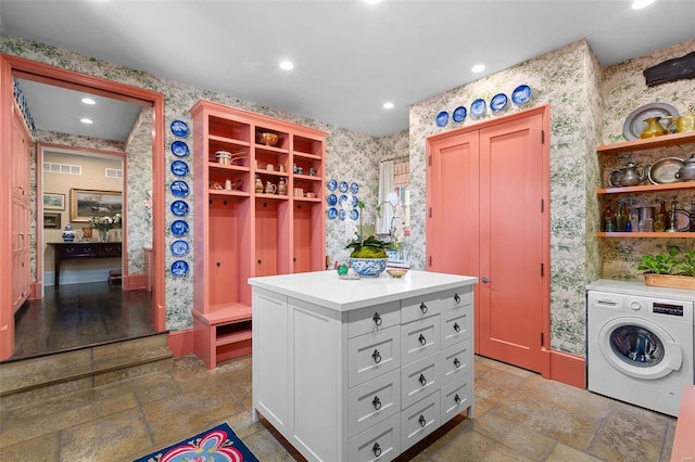 washroom with visible vents, wallpapered walls, laundry area, washer / clothes dryer, and stone tile flooring