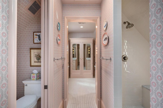 bathroom featuring visible vents, wallpapered walls, a tile shower, tile patterned floors, and toilet