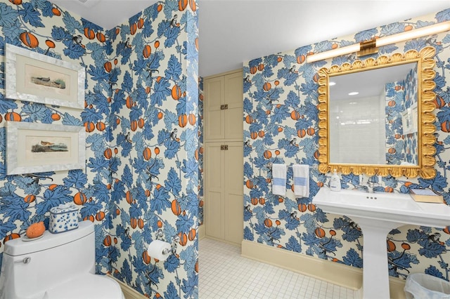 half bathroom with tile patterned floors, toilet, and wallpapered walls