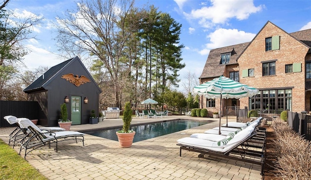 view of pool featuring an outbuilding, a fenced in pool, a patio area, and fence