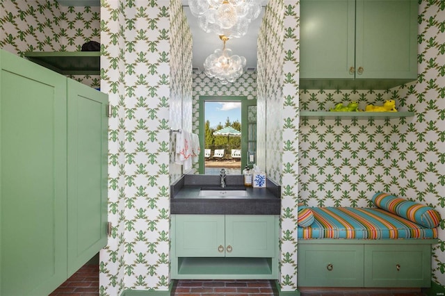 bathroom with wallpapered walls, an inviting chandelier, brick floor, and a sink