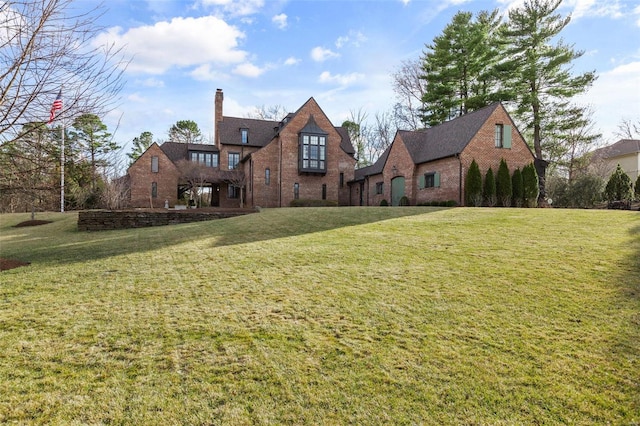 back of house featuring a lawn, a chimney, and brick siding