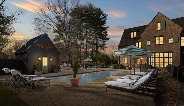 pool at dusk featuring a patio area and an outdoor pool