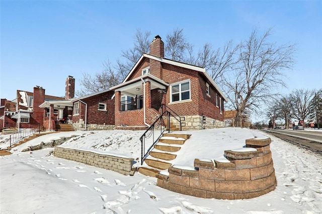 view of front of home featuring brick siding and a chimney