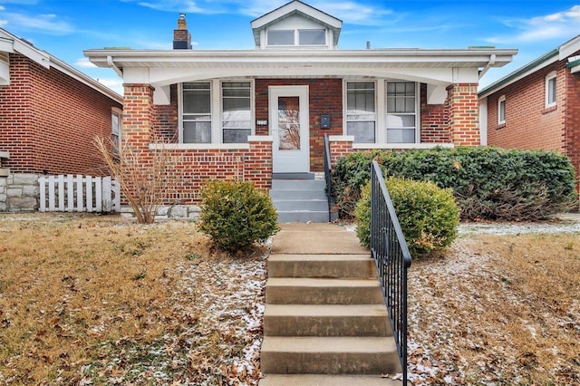 bungalow featuring a porch and brick siding