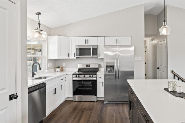 kitchen with light countertops, appliances with stainless steel finishes, dark wood-type flooring, vaulted ceiling, and a sink