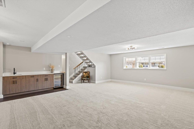 unfurnished living room featuring wine cooler, carpet flooring, baseboards, stairway, and wet bar