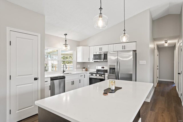 kitchen featuring lofted ceiling, appliances with stainless steel finishes, dark wood-style flooring, white cabinetry, and a sink