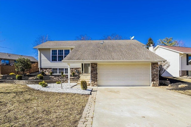 view of front of house featuring a shingled roof, concrete driveway, stone siding, an attached garage, and fence