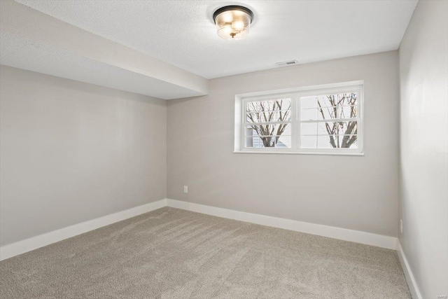 unfurnished room featuring visible vents, baseboards, a textured ceiling, and light colored carpet