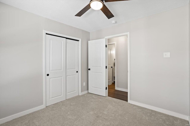 unfurnished bedroom with baseboards, a ceiling fan, a textured ceiling, carpet floors, and a closet