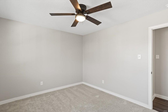 carpeted spare room with a textured ceiling, a ceiling fan, and baseboards