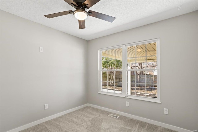 carpeted spare room featuring a textured ceiling, a ceiling fan, visible vents, and baseboards