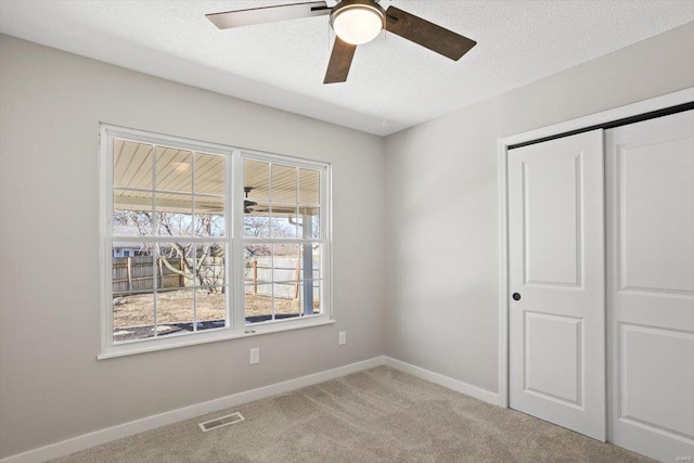 unfurnished bedroom featuring baseboards, visible vents, a textured ceiling, and carpet flooring