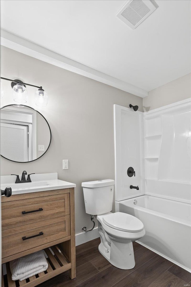 bathroom featuring toilet, wood finished floors, vanity, visible vents, and tub / shower combination