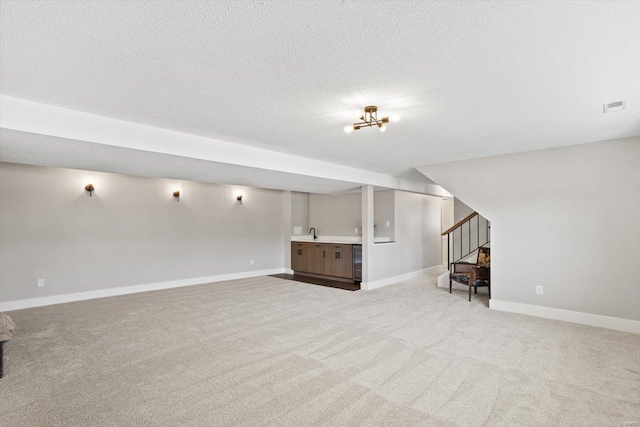 finished basement with visible vents, a sink, stairway, and a textured ceiling