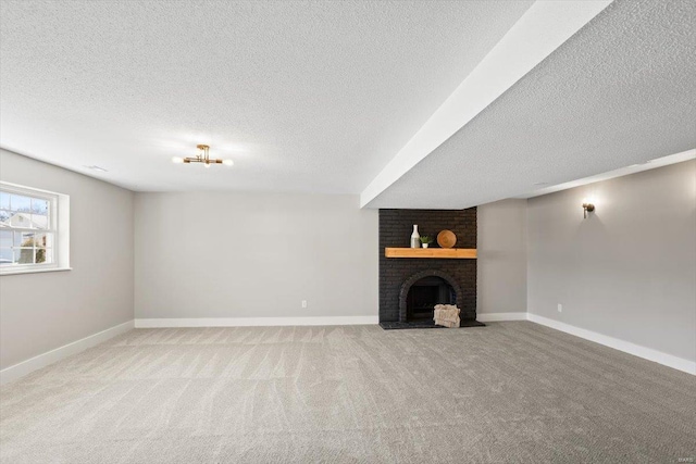 basement with carpet, a textured ceiling, a brick fireplace, and baseboards