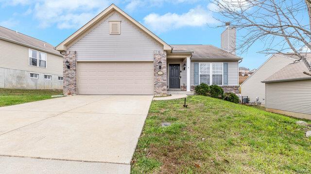 view of front facade with an attached garage, driveway, brick siding, and a front yard