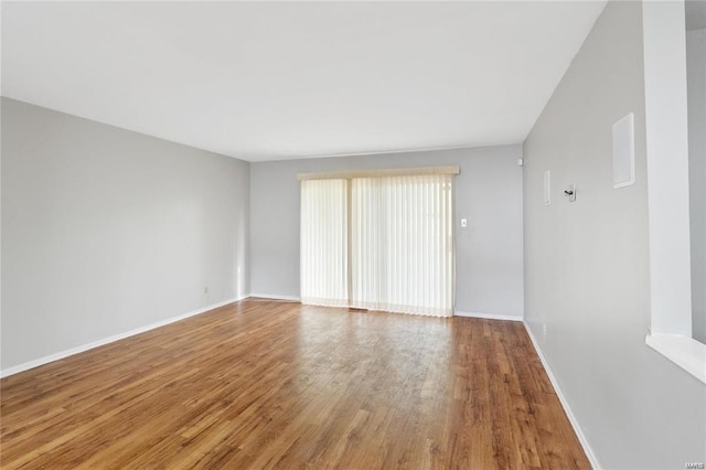 unfurnished room with baseboards and wood finished floors