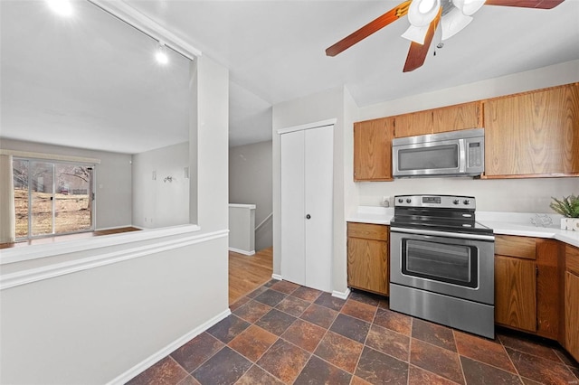 kitchen featuring appliances with stainless steel finishes, brown cabinetry, light countertops, and stone tile floors