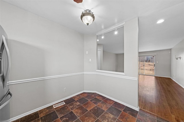 interior space with rail lighting, baseboards, visible vents, and stone tile floors