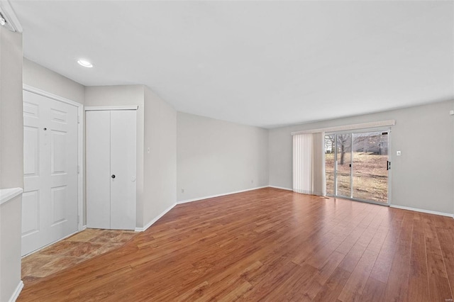 unfurnished living room with recessed lighting, wood finished floors, and baseboards