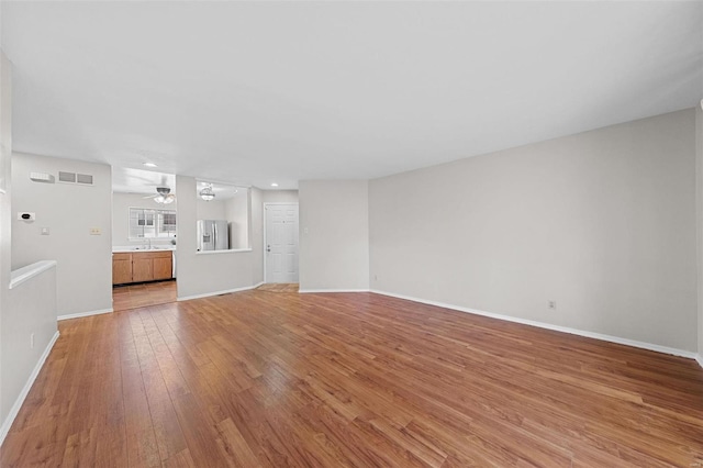 unfurnished living room with light wood-style flooring, visible vents, and baseboards