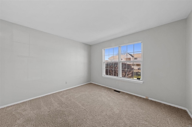 empty room featuring carpet floors, visible vents, and baseboards