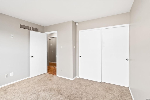 unfurnished bedroom with carpet floors, baseboards, visible vents, and a closet