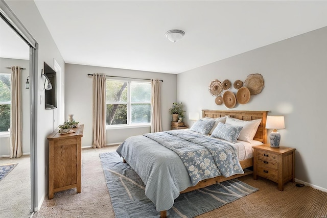 bedroom with light carpet, multiple windows, and baseboards