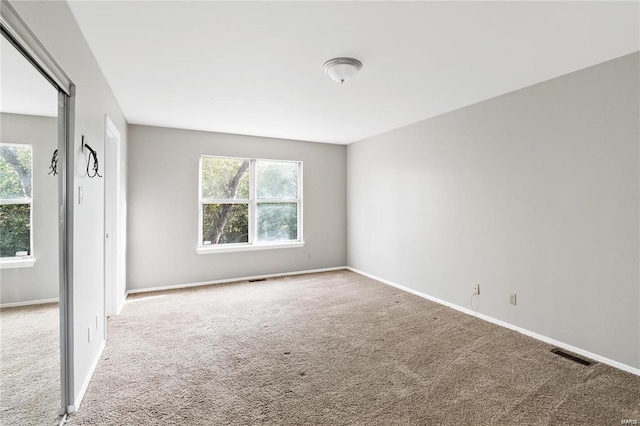 spare room featuring carpet, visible vents, and baseboards