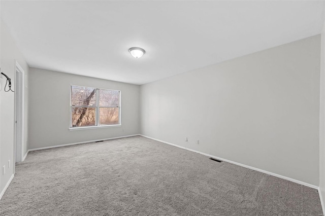 unfurnished room with carpet flooring, visible vents, and baseboards