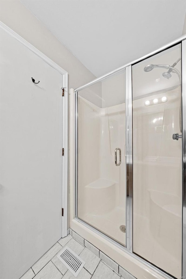 bathroom with a stall shower, visible vents, and tile patterned floors