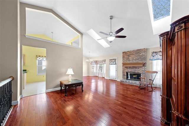 living room with high vaulted ceiling, a brick fireplace, a skylight, and hardwood / wood-style flooring