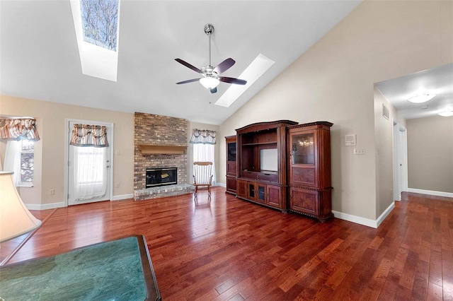 unfurnished living room featuring a skylight, wood-type flooring, a ceiling fan, a brick fireplace, and high vaulted ceiling