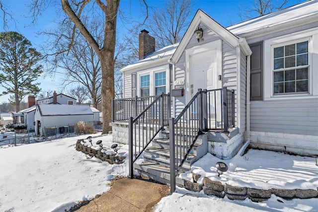 snow covered property entrance featuring a chimney