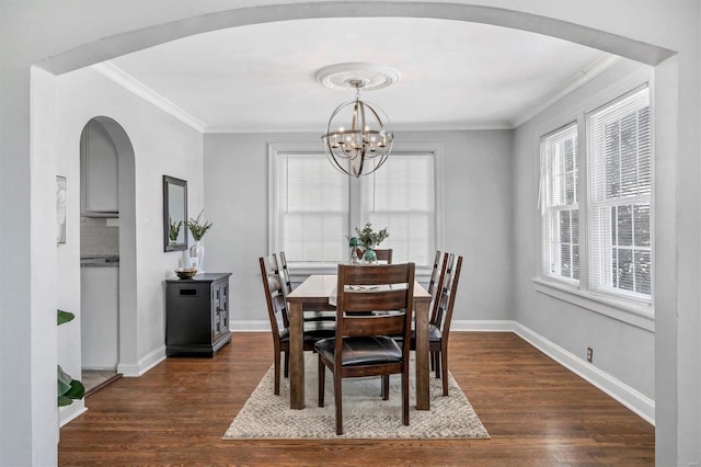 dining space featuring dark wood-type flooring, crown molding, baseboards, and an inviting chandelier