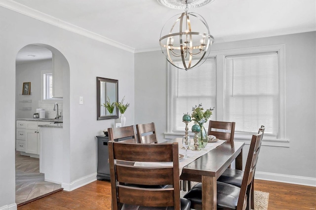 dining room with baseboards, arched walkways, dark wood-style floors, ornamental molding, and an inviting chandelier