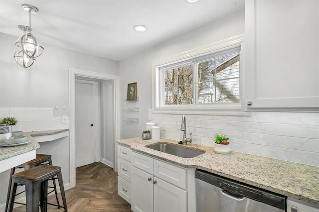 kitchen featuring dishwasher, white cabinetry, a sink, and decorative light fixtures