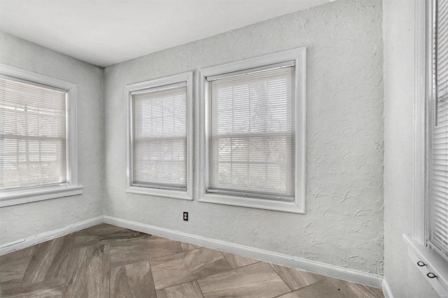 empty room featuring a textured wall and baseboards