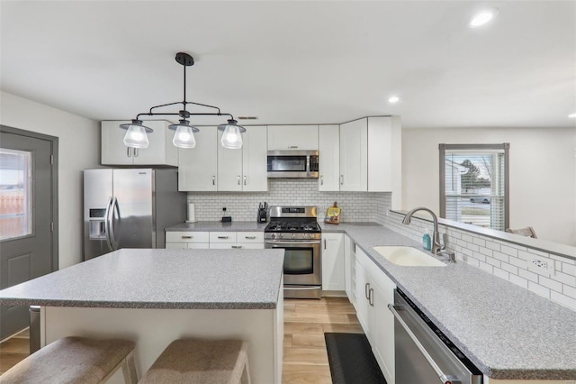 kitchen with decorative backsplash, a breakfast bar area, appliances with stainless steel finishes, light wood-type flooring, and a sink